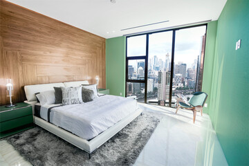 Obraz premium Modern and contemporary bedroom in Melbourne with views of the financial district of the city. Condo or Hotel accommodation. Pale green, maple and gray colors.