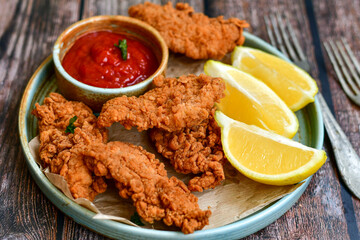 
 Crispy  deep fried   chicken strips and wedges potato. Breaded  with cornflakes chicken  breast fillets  with chilly peppers and fresh   basil on wooden rustic background