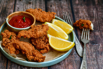 
 Crispy  deep fried   chicken strips and wedges potato. Breaded  with cornflakes chicken  breast fillets  with chilly peppers and fresh   basil on wooden rustic background