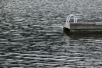 Floating dock with swimming ladder on a lake with ripples.