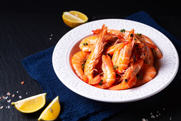 Food concept fresh boiled Shimps in ceramic plate on black slate stone board with copy space