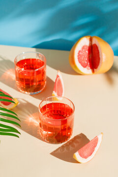 two glasses with grapefruit cocktail on a beige-blue background on a sunny day. Apperole.