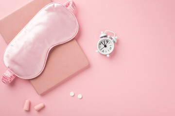 Top view photo of pink silk sleeping mask small white alarm clock pills earplugs and pink organizer on isolated pastel pink background with copyspace