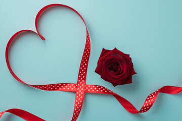 Top view photo of saint valentine's day decorations red rose and red ribbon heart on isolated pastel blue background with empty space