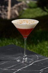 Red cocktail with froth and shaving on restaurant table