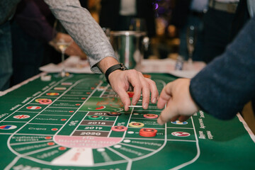 Close-up, hands of people playing in a wine casino, a man's hand with game chips on a green background of the table. Casino concept
