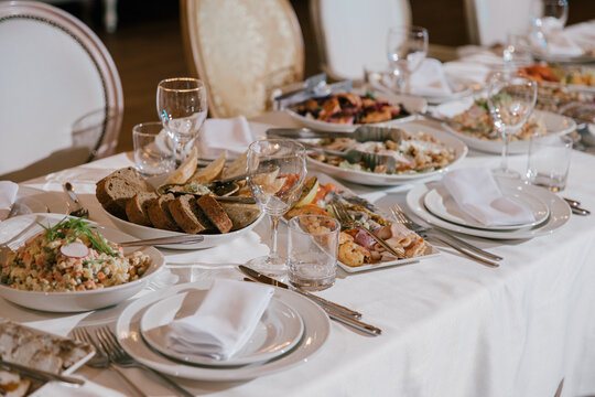 Table Setting For A Banquet Or Celebration.Empty Glasses For Alcoholic Beverages, Wine And Juice, A Set Table.Cloth Napkins On A White Platter And Cutlery On The Table.Cold Appetizers And Salads