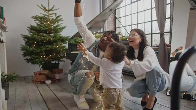 Happy interracial family playing with child christmas lights - wide shot. High quality 4k footage