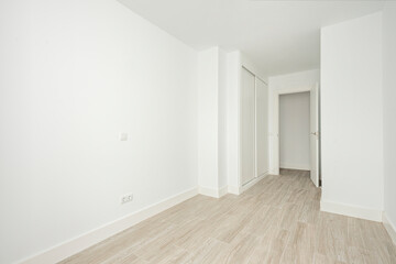 Empty white room with built-in wardrobes and wooden-like ceramic floors