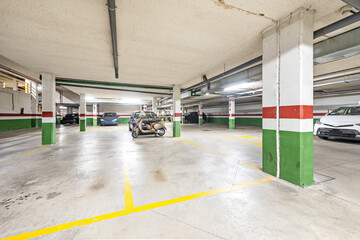 Garage with concrete track in residential apartment building with cars and bicycles