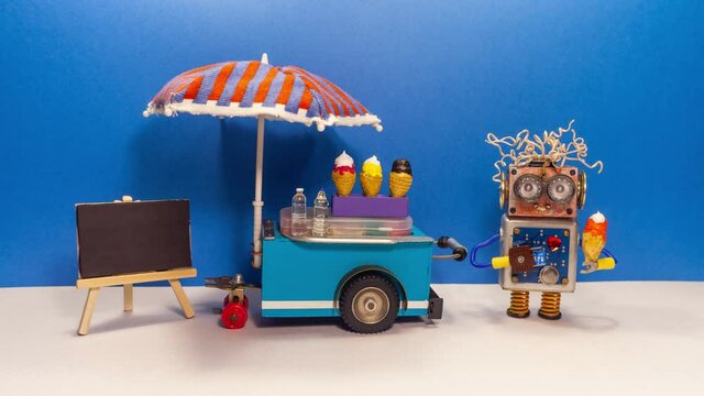 Mobile ice cream cart and robot seller. A funny smiling robotics shopman with ice cream cone. Empty black chalkboard for menu. blue wall background.
