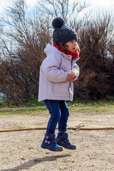 Little girl with hat and red scarf playing in the field. Children with winter clothes