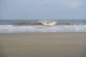 Bei stürmischem Wetter bricht eine Welle am Strand der Nordseeinsel Borkum. Dabei weht die Gischt...