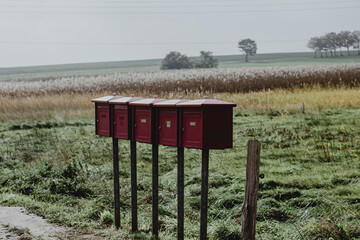 F&uuml;nf Briefk&auml;sten auf Holzpfosten in l&auml;ndlicher Umgebung
