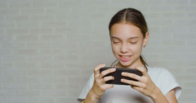 Teenager girl having fun while playing video game touching smartphone screen.
