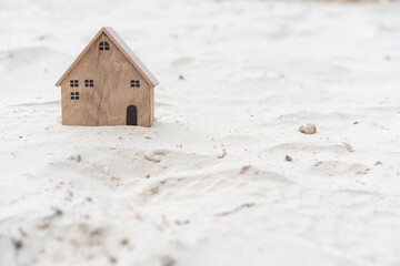 Obraz na płótnie Canvas Miniature wooden house on sand background