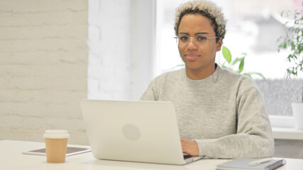 African Woman Shaking Head as No Sign while using Laptop in Office