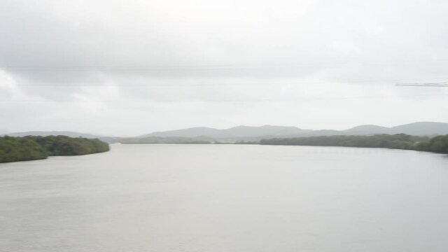 HD scenery of the Zuari river flowing through Borim village in Goa India with a view of a shipbuilding company and Borim Bridge