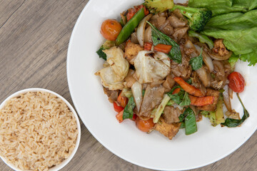 Overhead view of pad kee mao authentic Thai food served with a side order of brown rice for a complete meal