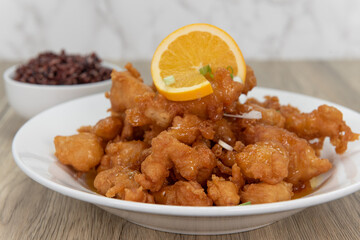 Breaded orange chicken crispy on the outside with sliced citrus twist on top of generous pile of food