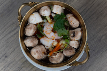 Overhead view of ornate decorated brass bowl with tom yung goong shrimp soup served hot and ready to slurp
