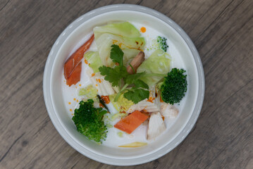 Overhead view of hearty bowl of Tom Kah with vegetables and tofu served in a white sauce soup for a healthy meatless meal