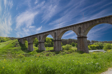 Fototapeta na wymiar Viaduct. Beautiful old arched stone railway bridge against the backdrop of a scenic landscape