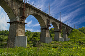 Fototapeta na wymiar Viaduct. Beautiful old arched stone railway bridge against the backdrop of a scenic landscape