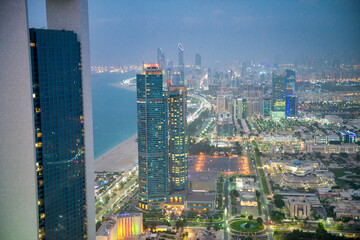 Abu Dhabi aerial skyline at night. City tall buildings along Corniche Road.