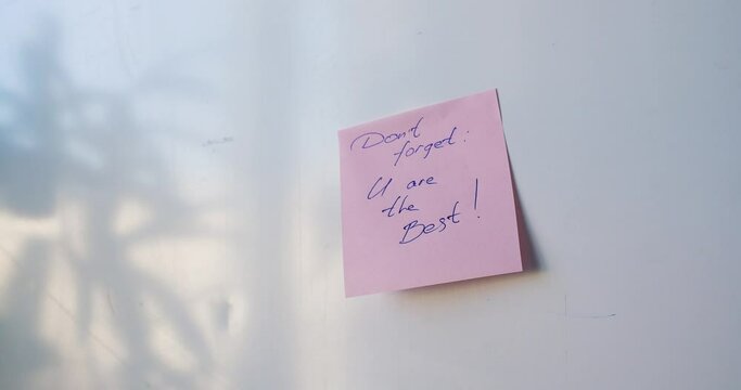 Don't forget you are the best - a man's hand is pasting a reminder sticker.