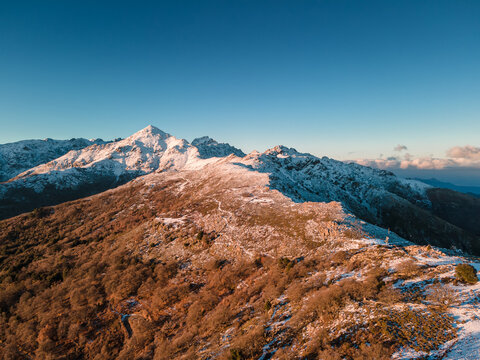 Aerial view of a ridge at the Col de Battaglia leading towards the snow covered peak of Monte San Parteo in the Balagne region of Corsica