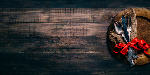 Valentines dinner setting with vintage silverware, dinner plate and red ribbon on wooden table....