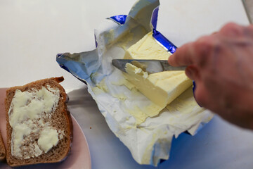 The woman cuts the butter and spreads the bread
