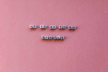 Motivational sentence "it is ok to be single" - white letters on a pink background © Gosia