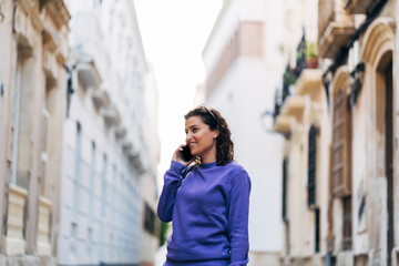 Fototapeta premium Cheerful man talking on smartphone on street