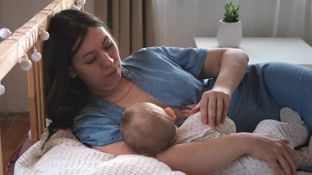 Mother breastfeeding baby at home. Mom nursing infant nurturing. Portrait of Child suckling milk from breast. Authentic shot of mother is breastfeeding her newborn baby. Close Up. Concept of maternity