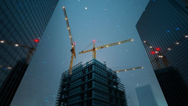 Big cranes in a city centre against a beautiful starry night sky. Tower cranes.