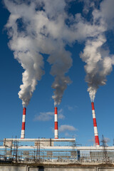 smoke comes from three pipes against the background of a clear blue sky.
