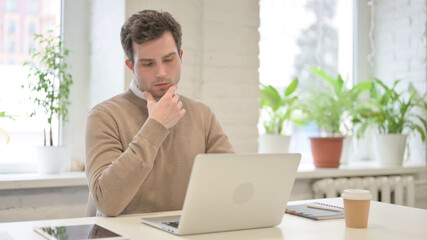 Man Thinking while Working on Laptop in Office