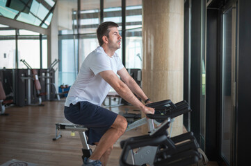 Naklejka na ściany i meble Man exercising in the gym riding stationary bike indoor cycling