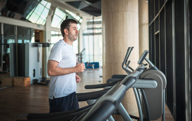 Man jogging on a treadmill during a cardio running warmup exercise in the gym