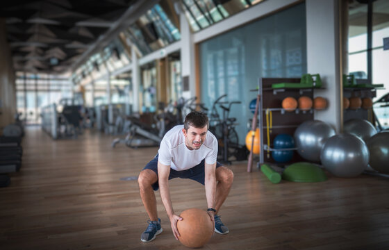 Man exercising in the gym with a heavy medicine slam ball