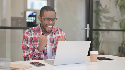 African Man Celebrating Success while using Laptop