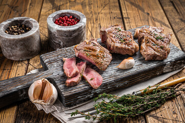 Roasted in BBQ lamb loin chops steaks, cutlets on a wooden board with herbs. Wooden background. Top view - obrazy, fototapety, plakaty