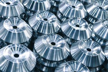 Metal products turned on a CNC milling machine, arranged in even rows, close-up with selective focus. 