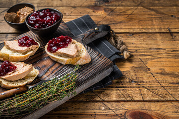 French cuisine Foie gras toasts, goose liver pate and lingonberry marmalade. wooden background. Top...
