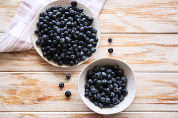 two bowls of blueberries with a saucer on a wooden background  top view 