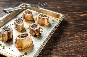 Roasted marrow beef bones in baking dish. Wooden background. Top view. Copy space - obrazy, fototapety, plakaty