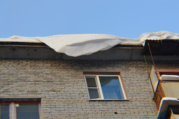 Snow hanging from the roof of a Five-storey house 