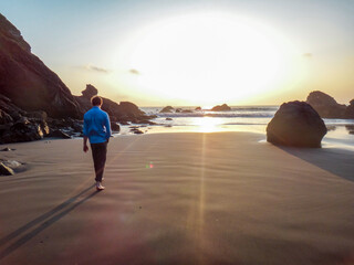 Man walks barefoot towards the ocean in a quiet cove